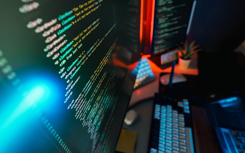 Computer screen filled with colourful code in blue and red ambient light